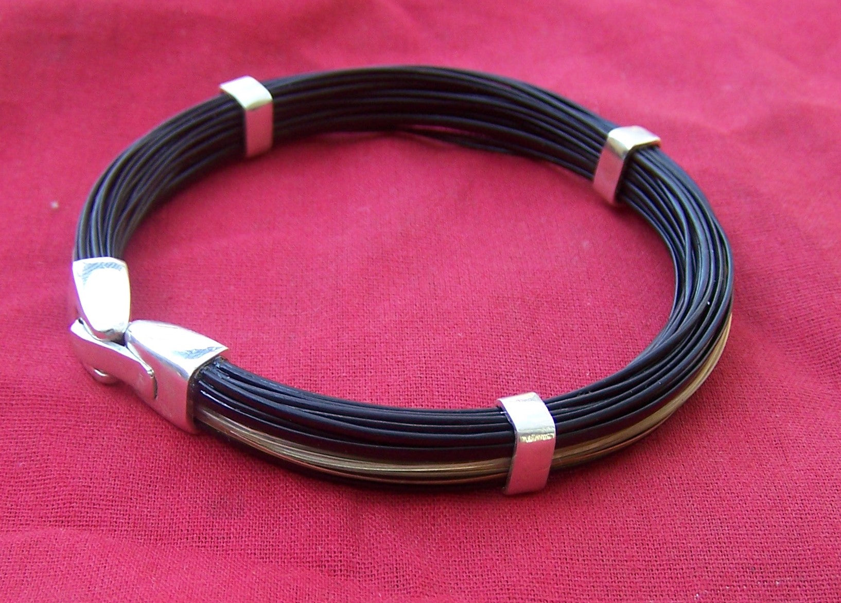 30 strands of dark elephant hair and 1 strand of giraffe hair caught between sterling silver angular bands with a sterling silver clip-close clasp. - SQ